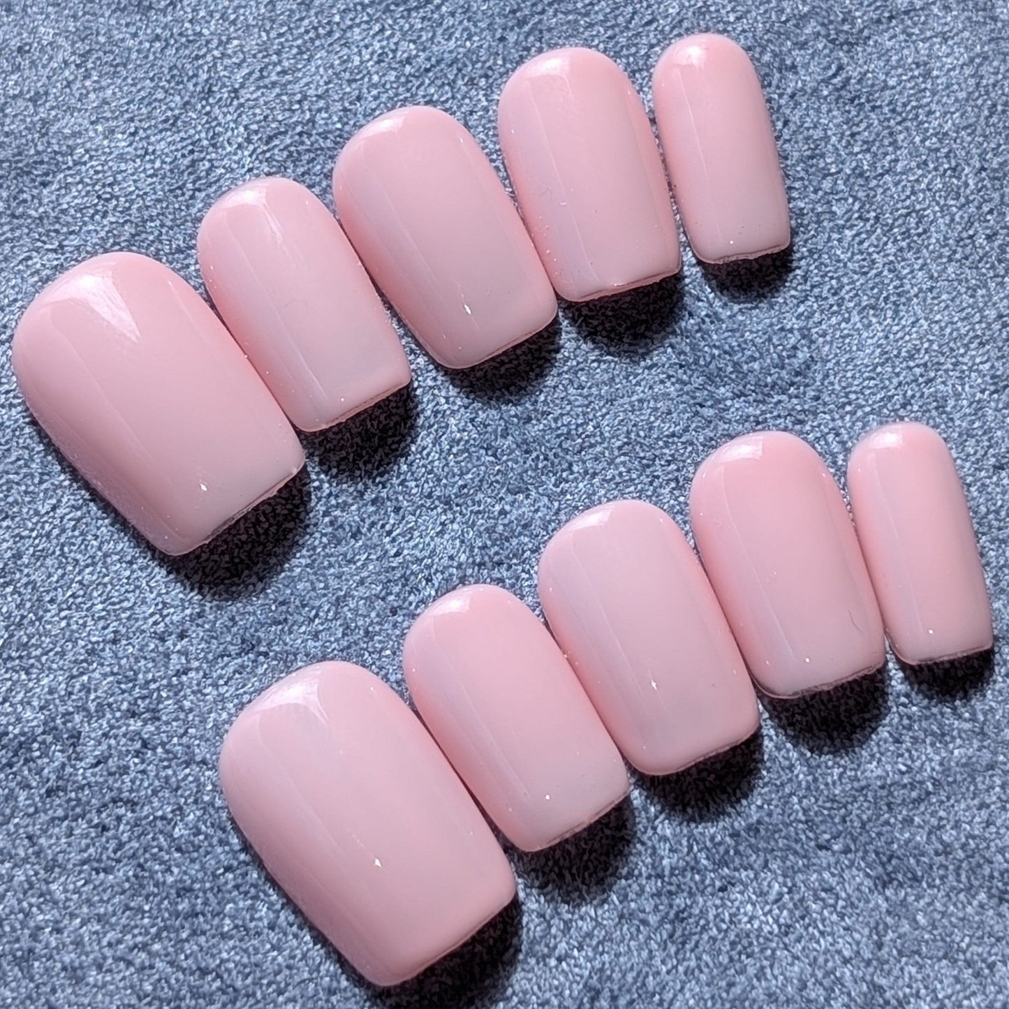 Handmade pale pink press-on nails in short square.
