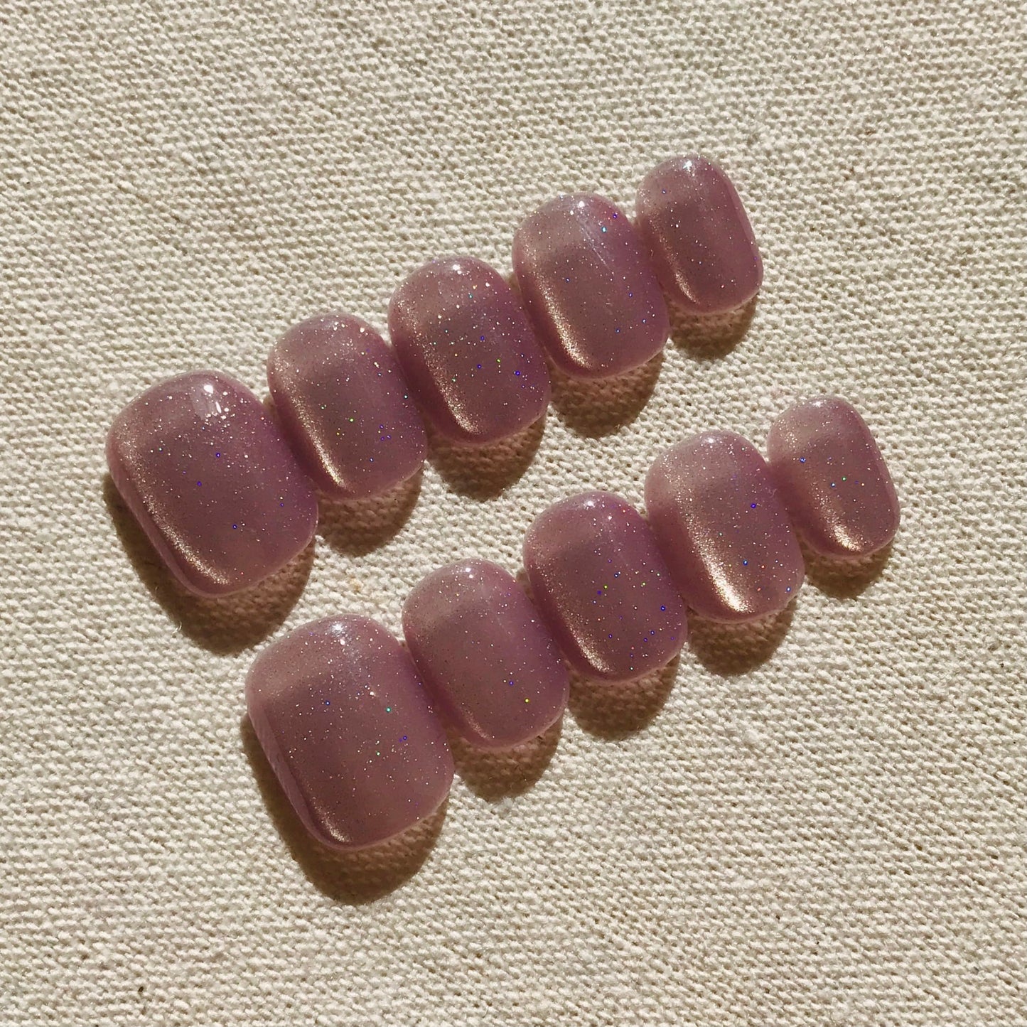 Calm Storm premium handmade press-on nails in light lavender with glittering cat eye effect in extra short round shape.