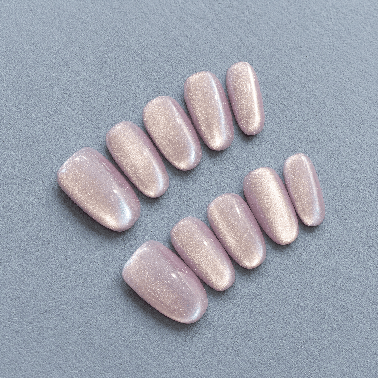 Oval shaped press-on nails with a glossy, shimmery pale lavender pink finish.