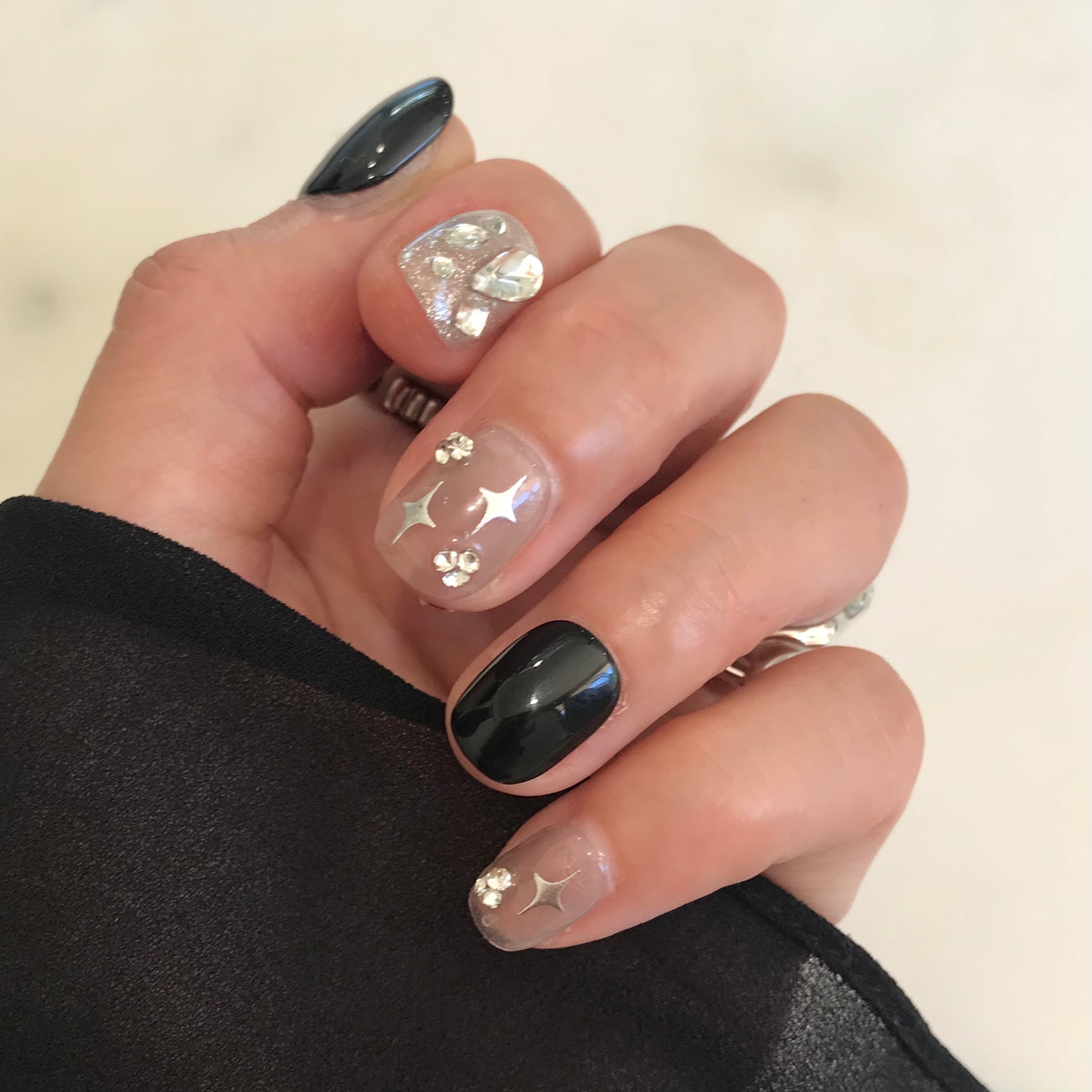 Hand with black and sliver sparkle press-on nails in extra short modern design. 
