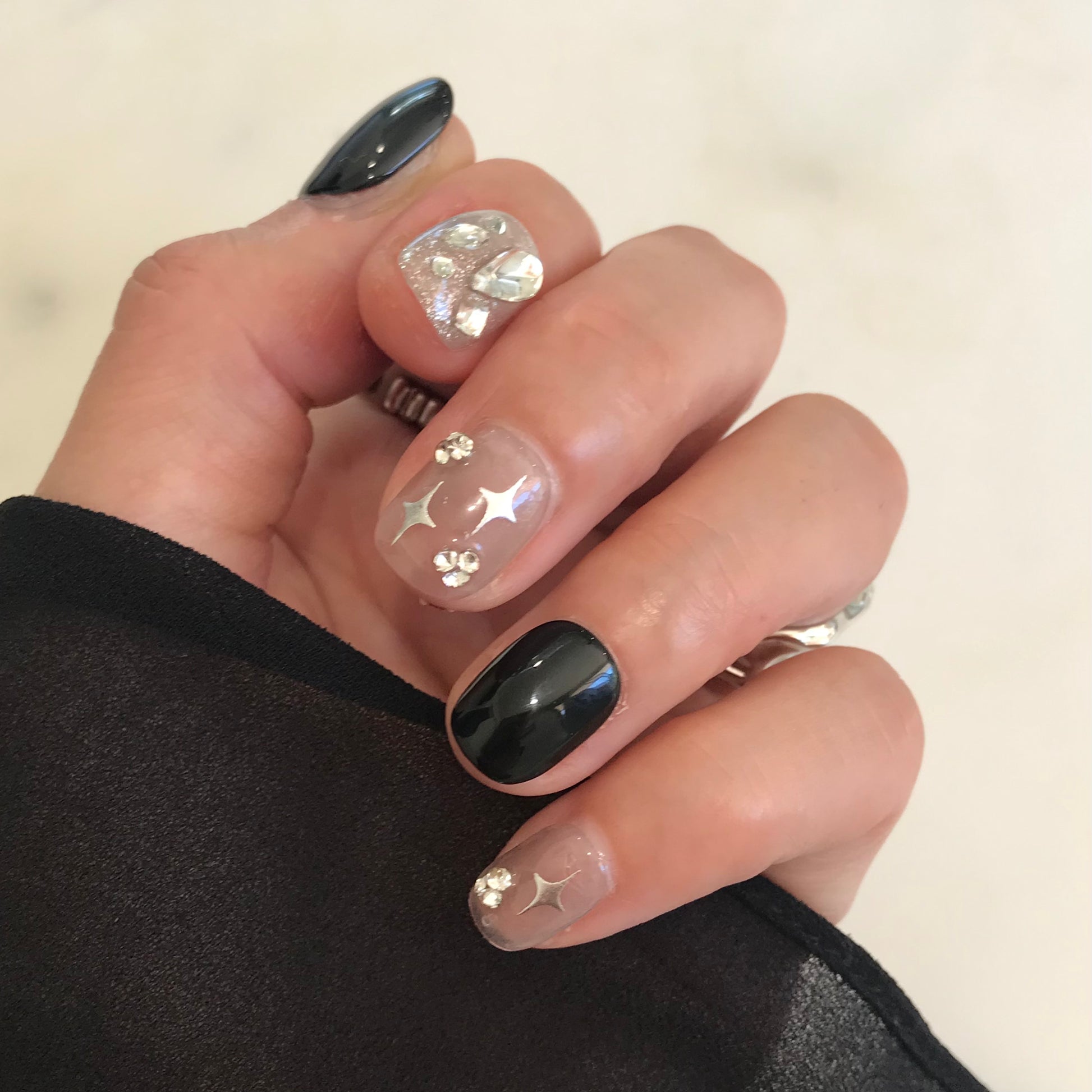 Hand with black and sliver sparkle press-on nails in extra short modern design. 
