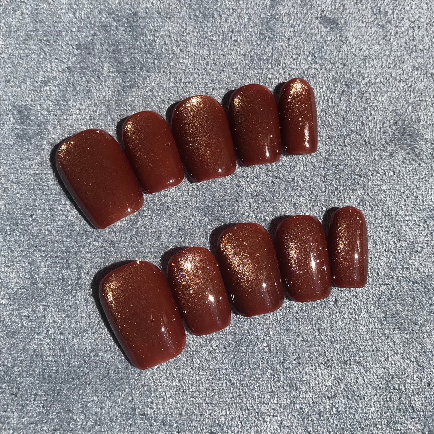 Calm Storm premium press-on nails with a glossy dark brown base and fine gold glitter.