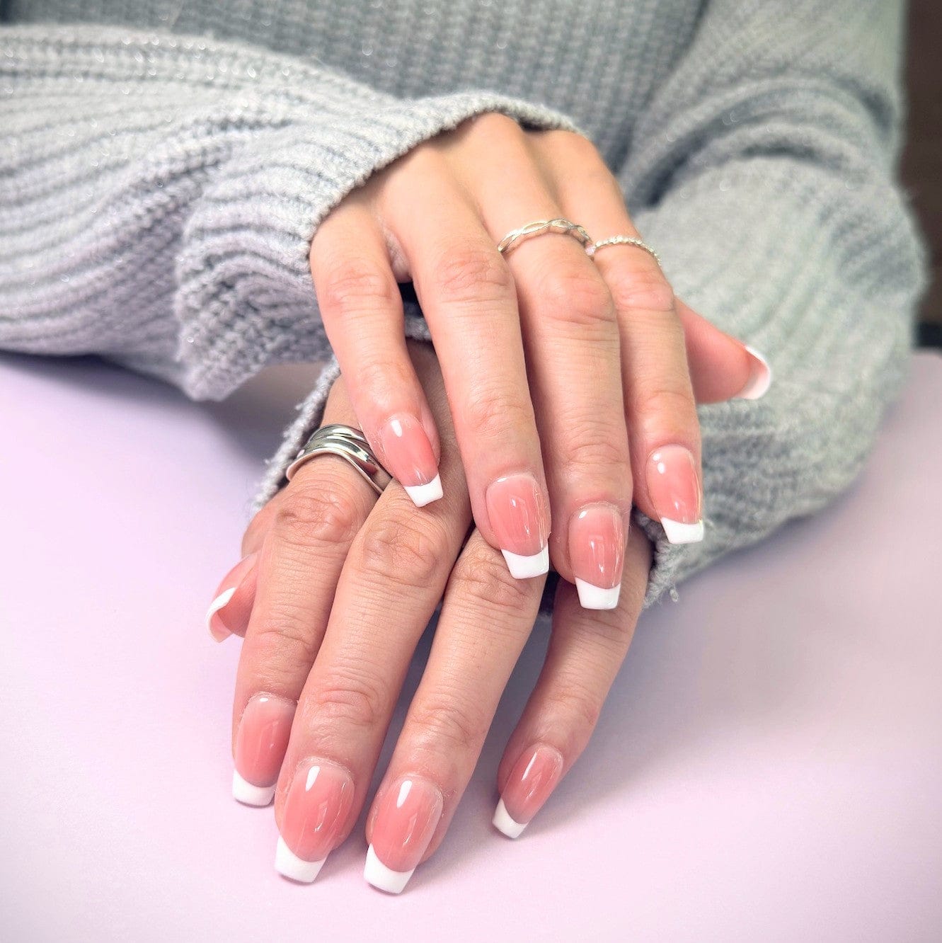Close-up of hands with salon quality French style press-on nails in medium square
