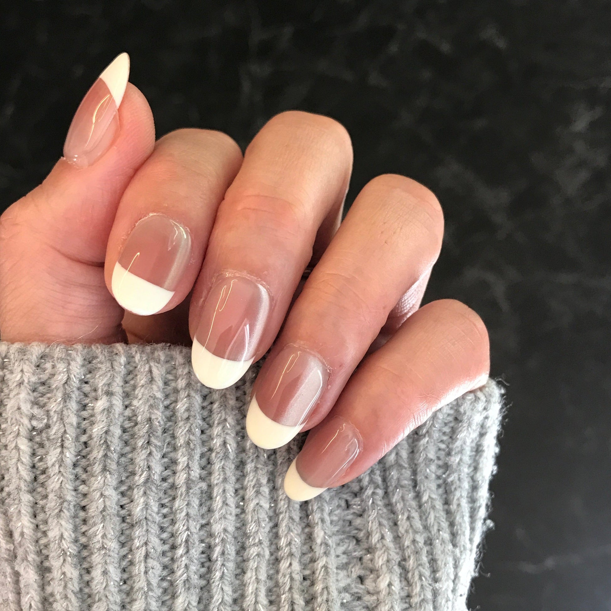 Close-up of a hand with glossy French manicure press-on nails 