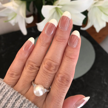 Hand with luxury glossy french tip press-on nails in cream