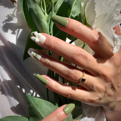 Lifestyle shot of green and white press-on nails with 3D floral designs in medium square.