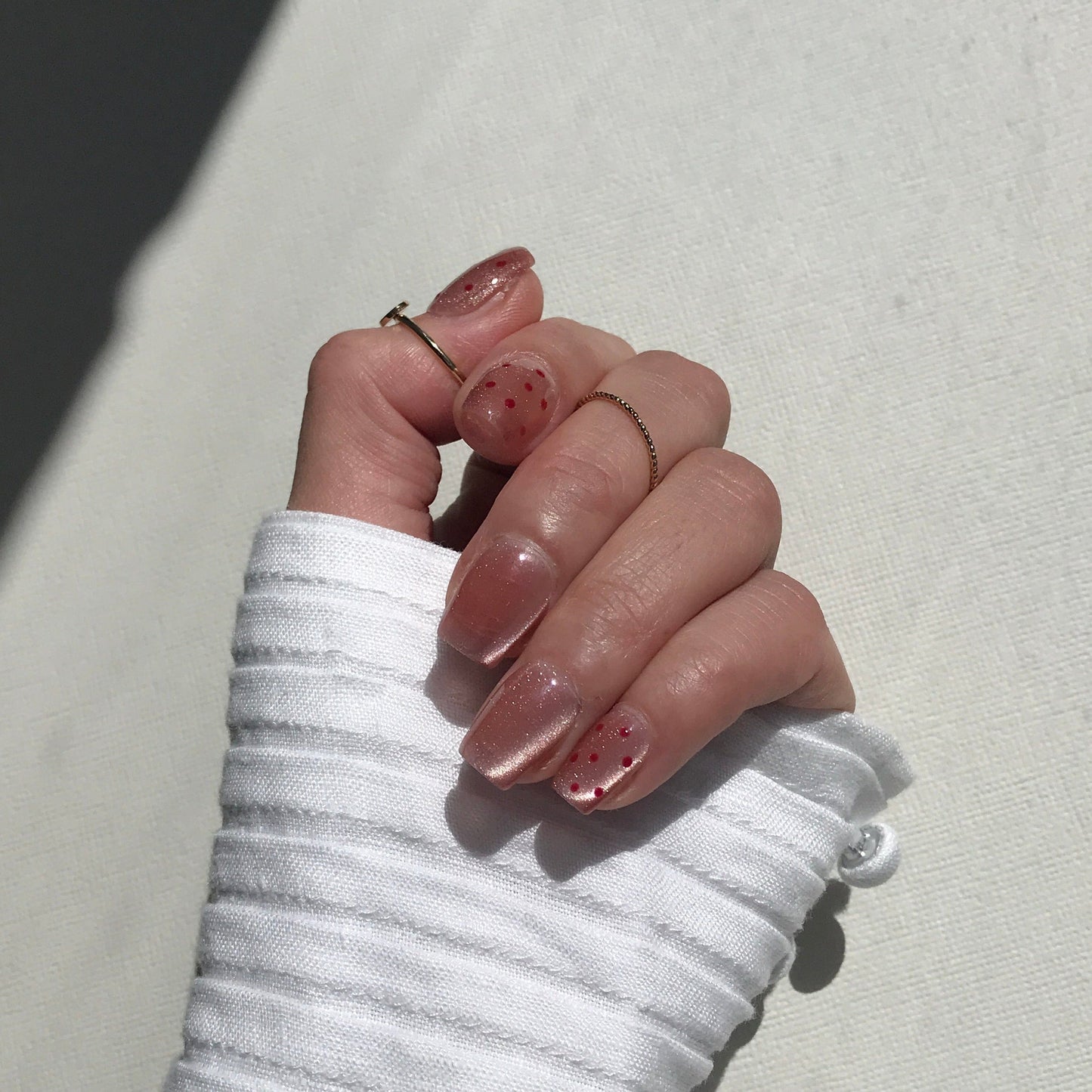 Close up of light pink press-on nails with cat eye and dotted design