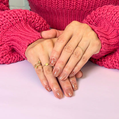 Hands modelling light pink, short square press-on nails with cat eye and dotted design