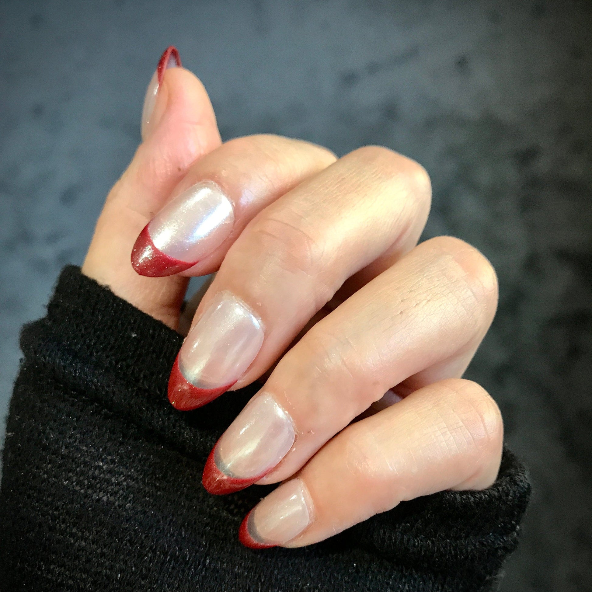 Close-up of a hand with handmade designer style chrome press-on nails with a red tip