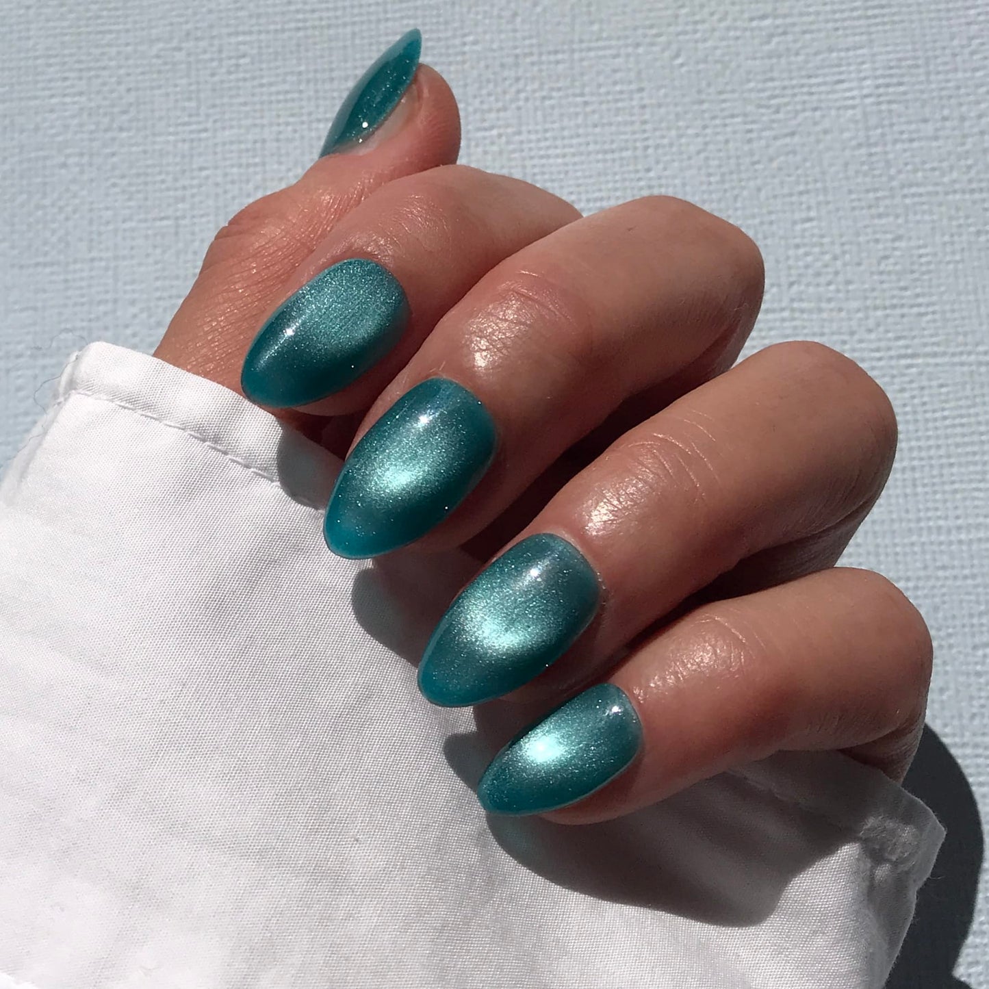 Luxury blue cat-eye press-on nails in short almond.
