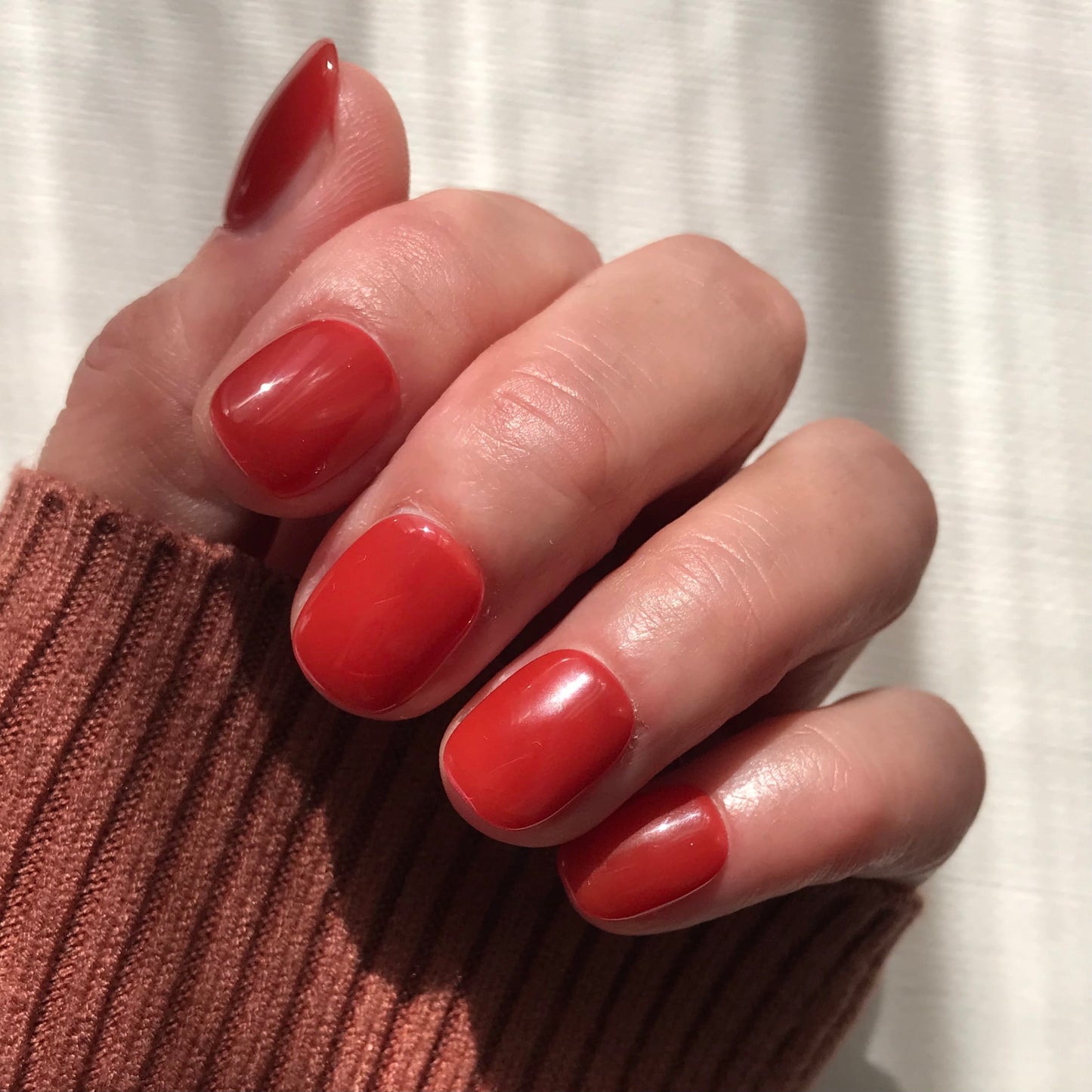 Close up of warm brick red press-on nails in salon quality high gloss.