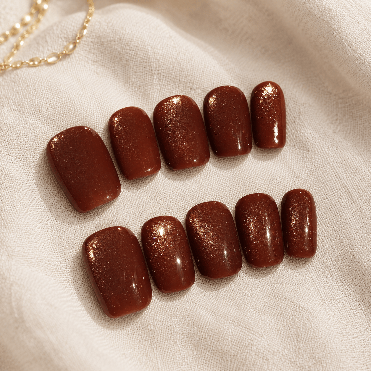 Calm Storm handmade press-on nails in a glossy dark brown color with a subtle gold shimmer.