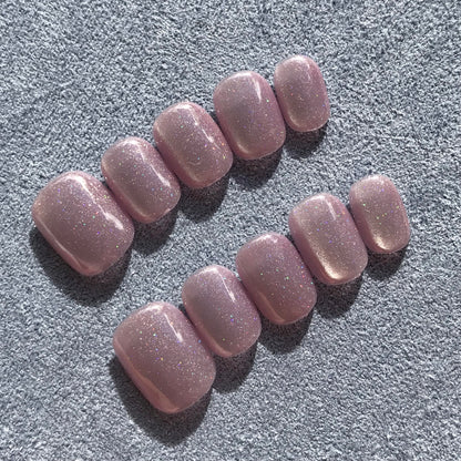 Close up of handmade press-on nails in light lavender with glittering cat eye effect in extra short round shape. 