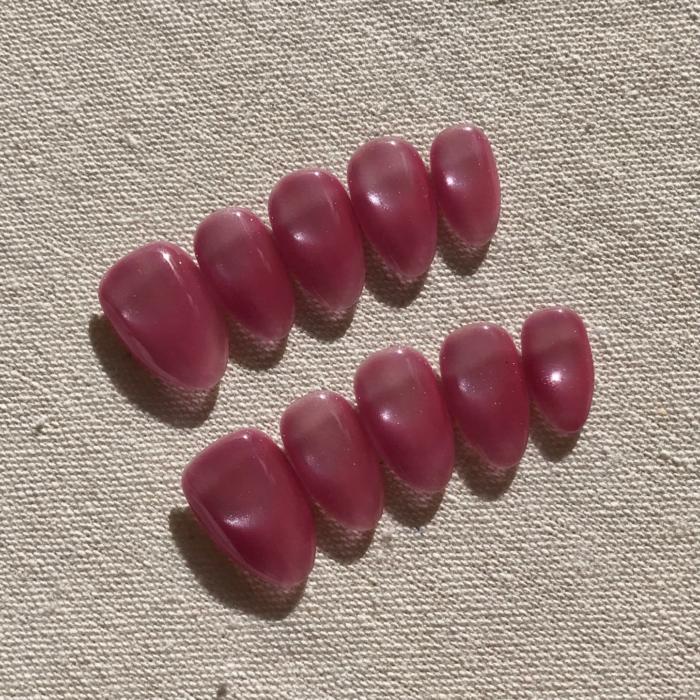 Calm Storm premium handmade pink press-on nails in medium almond with cat eye effect. 