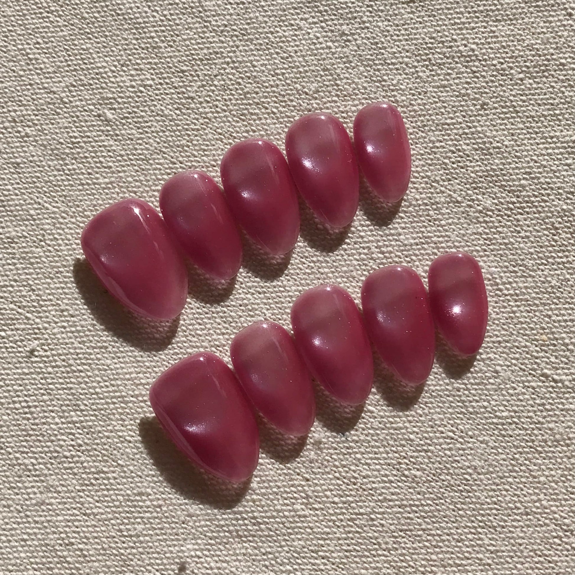 Calm Storm premium handmade pink press-on nails in medium almond with cat eye effect. 