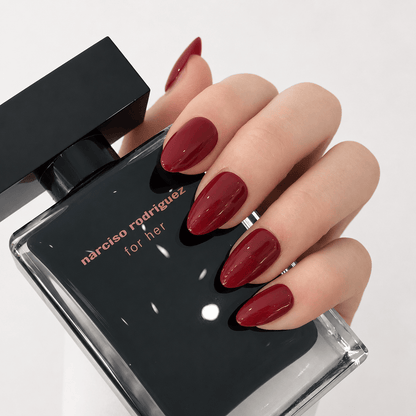 A hand with long, glossy classic red press on nails.