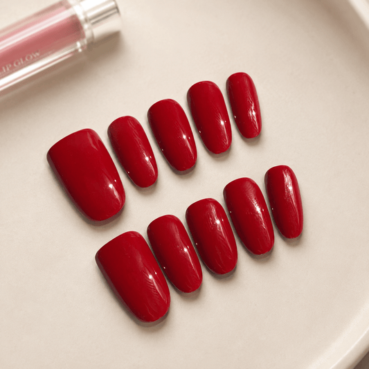Calm Storm handmade red press-on nails arranged on a light beige surface.