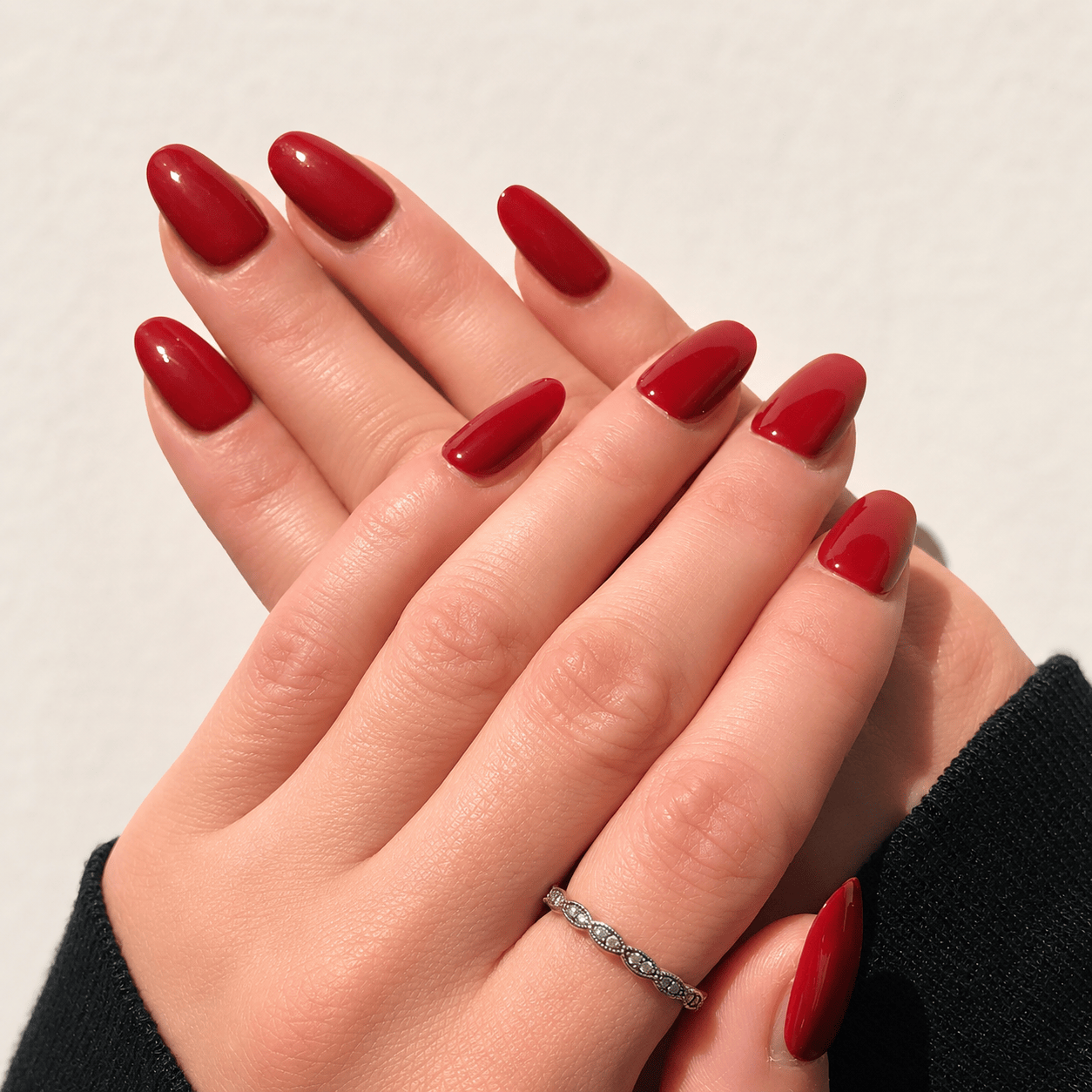 A close-up of a person's hands with long, glossy red press-on nails.