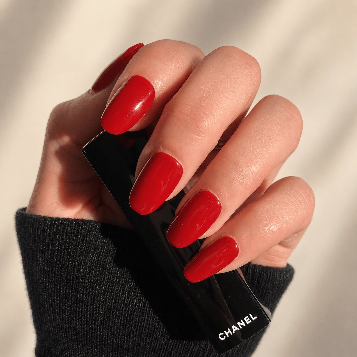 A close-up of a hand with glossy red press-on nails.