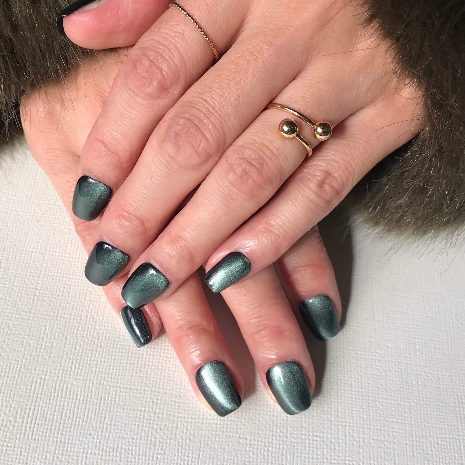 Luxury salon quality green press-on nails with cat eye effect in short square shape. 