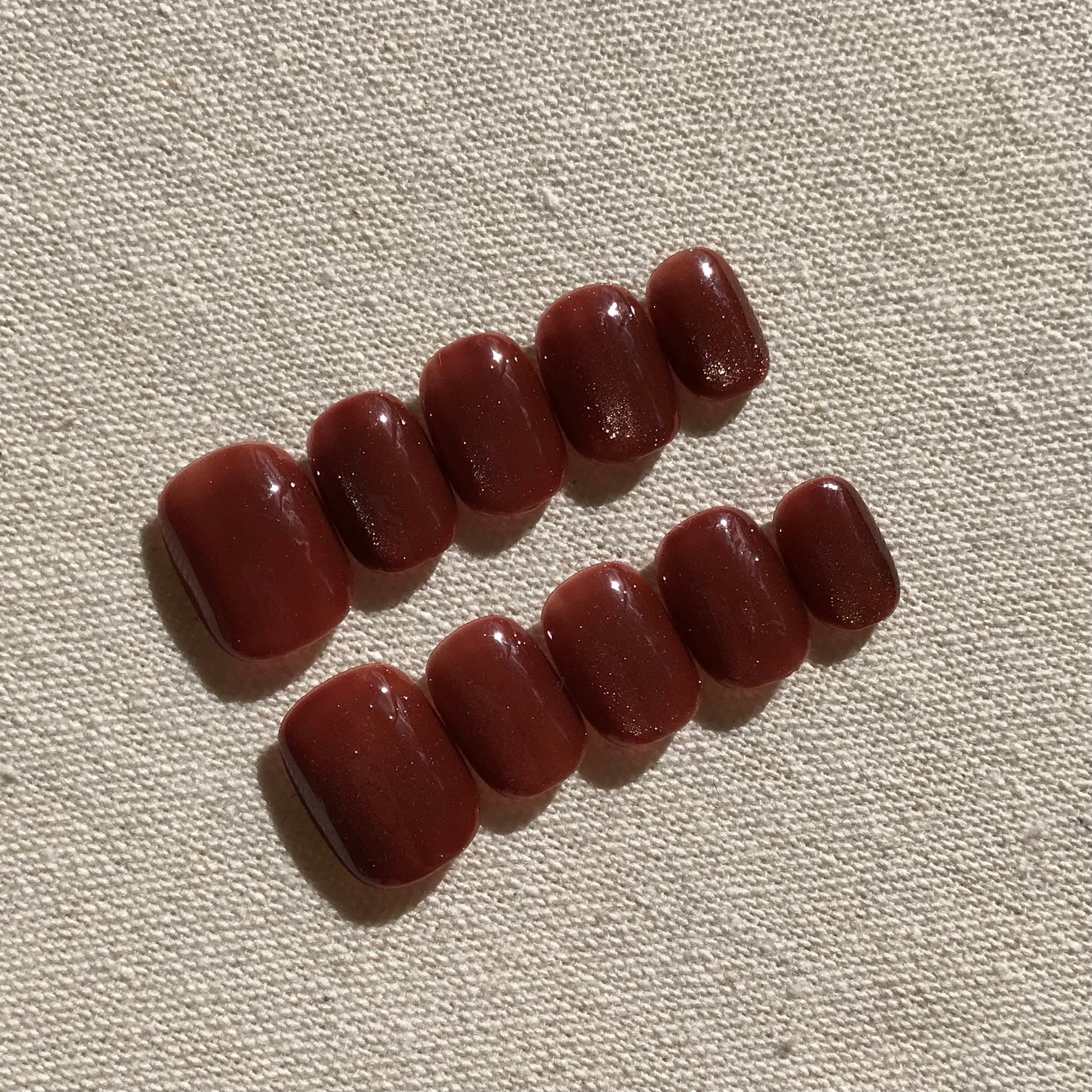 Calm Storm premium press-on nails in rich caramel cat eye effect in extra short round  shape.  