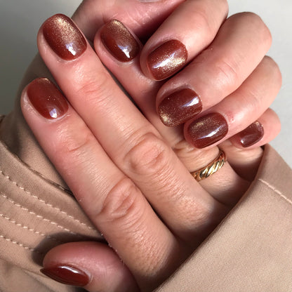 Close-up of hands with brown cat eye press-on nails.