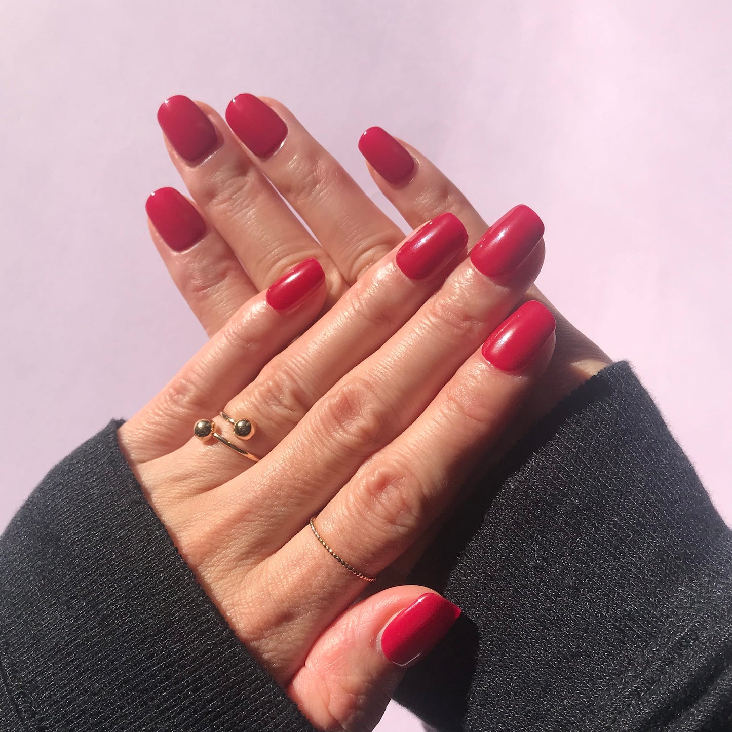 Hands modelling salon quality hot pink press-on nails in short square. 