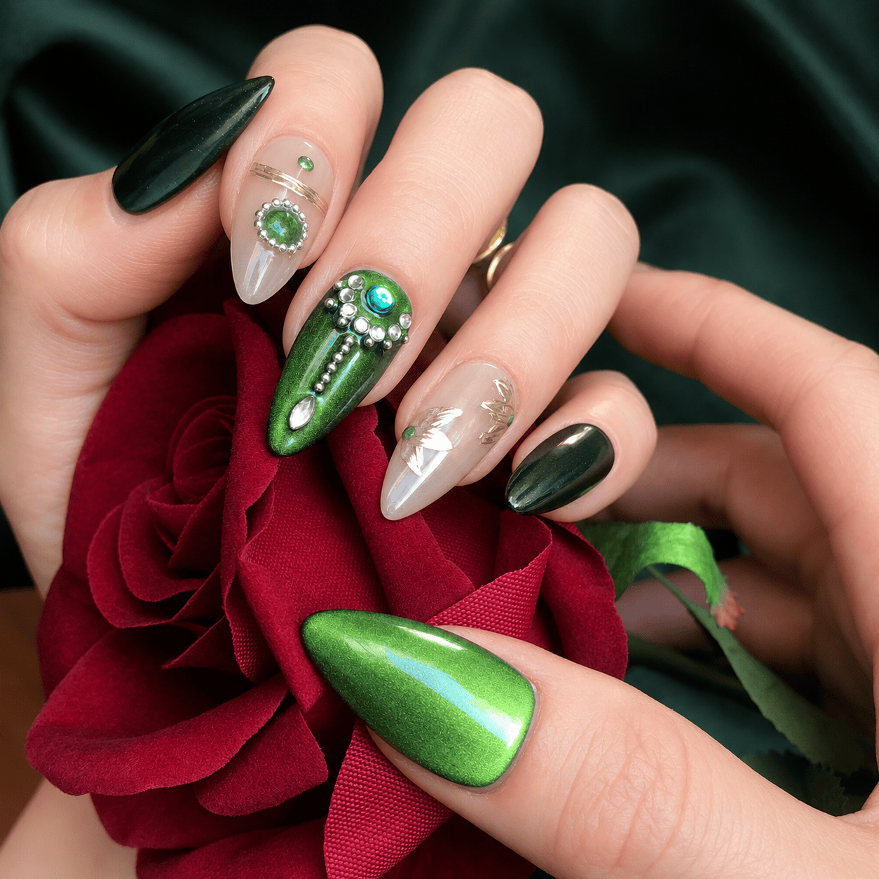 A close up of hand wearing emerald green press on nails with silver beads and diamonds. 