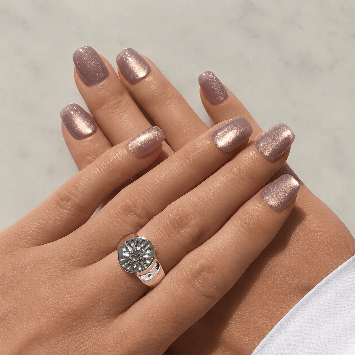A close up of press-on nails in light lilac with cat eye effect.