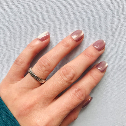 Hand wearing glittering light purple press-on nails.