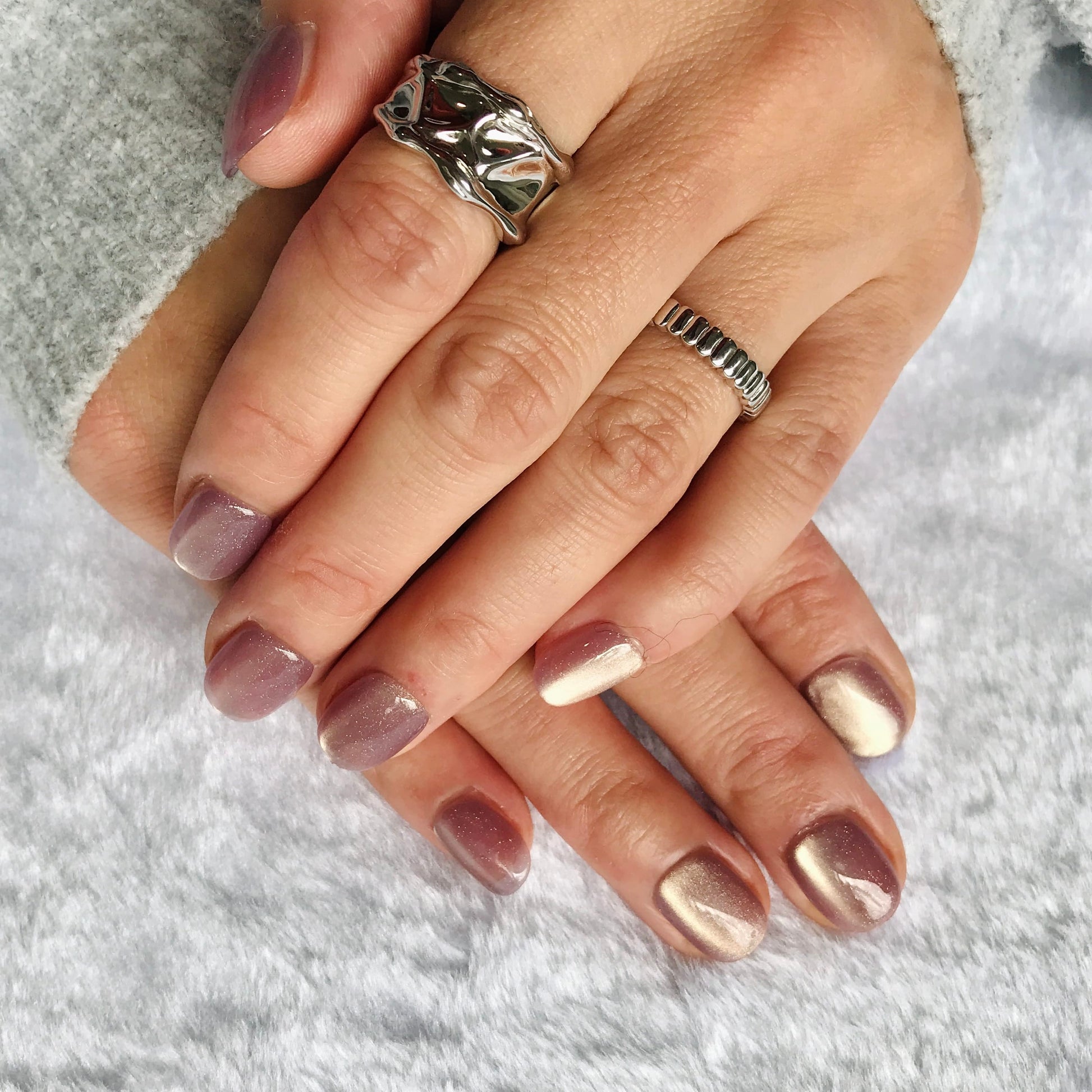 Hands modelling extra short lavender coloured press-on nails with cat eye design. 