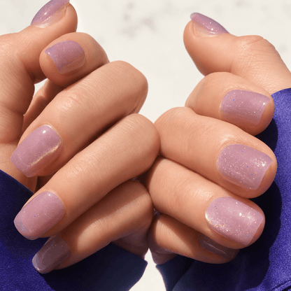 Lavender coloured press-on nails with glistening sparkle in short square. 