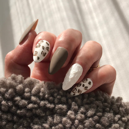 Close-up of a hand with stylish press-on nails with leopard print and 3D detail. 