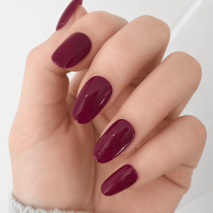 A close-up of glossy deep burgundy press on nails. 