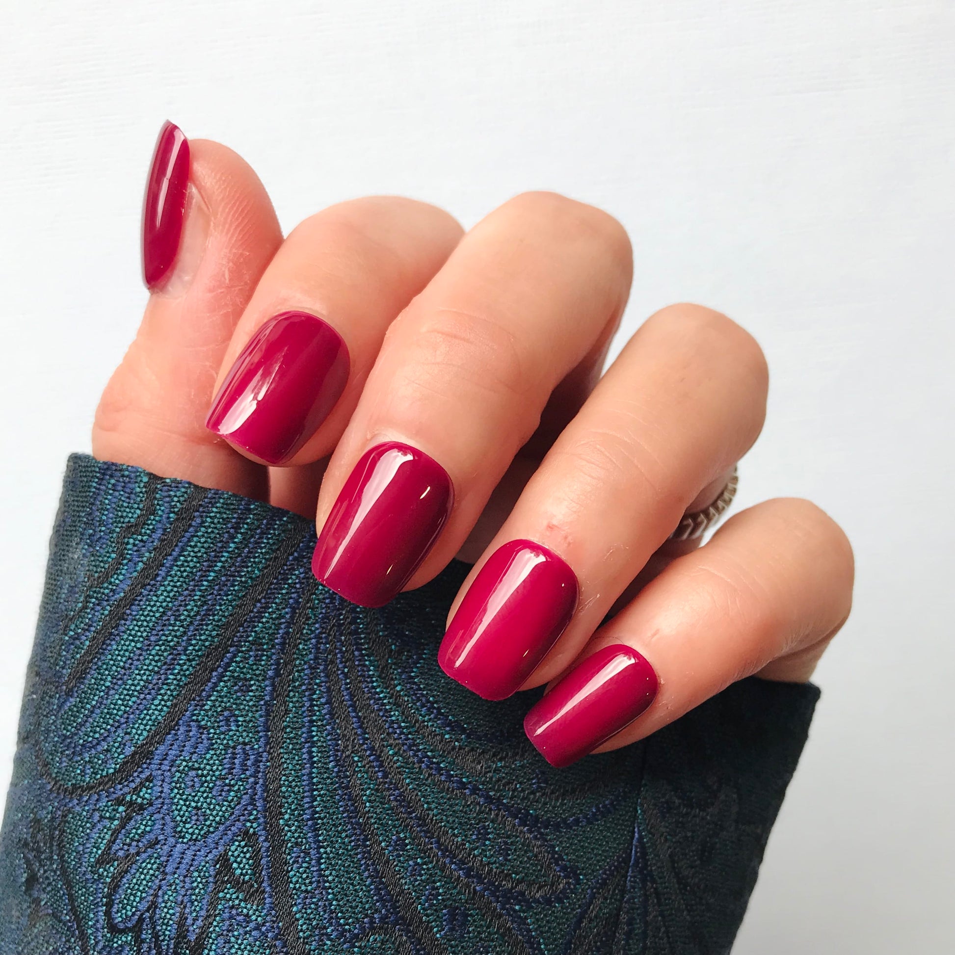 Close-up of a hand with luxury burgundy press-on nails.
