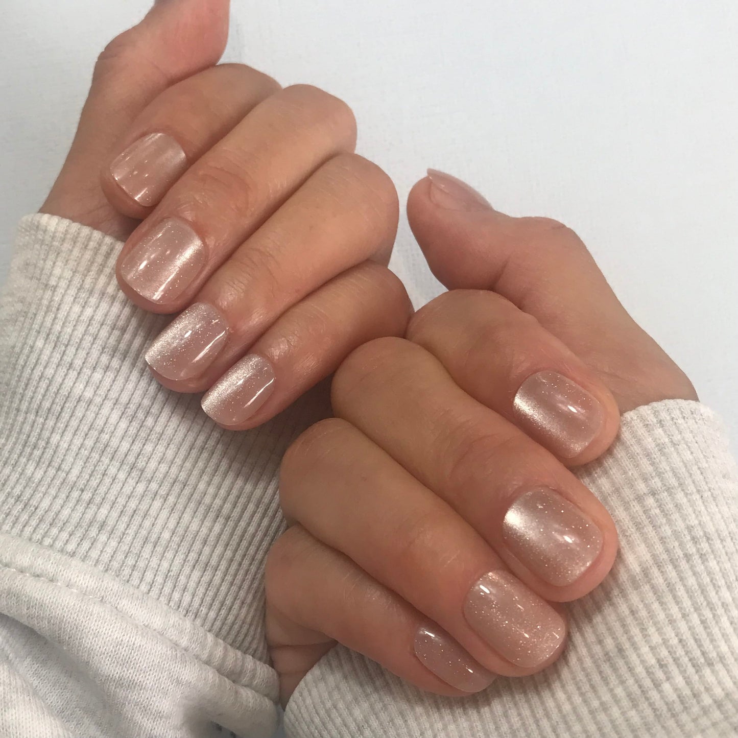 Close-up of hands with handmade pale pink press-on nails.