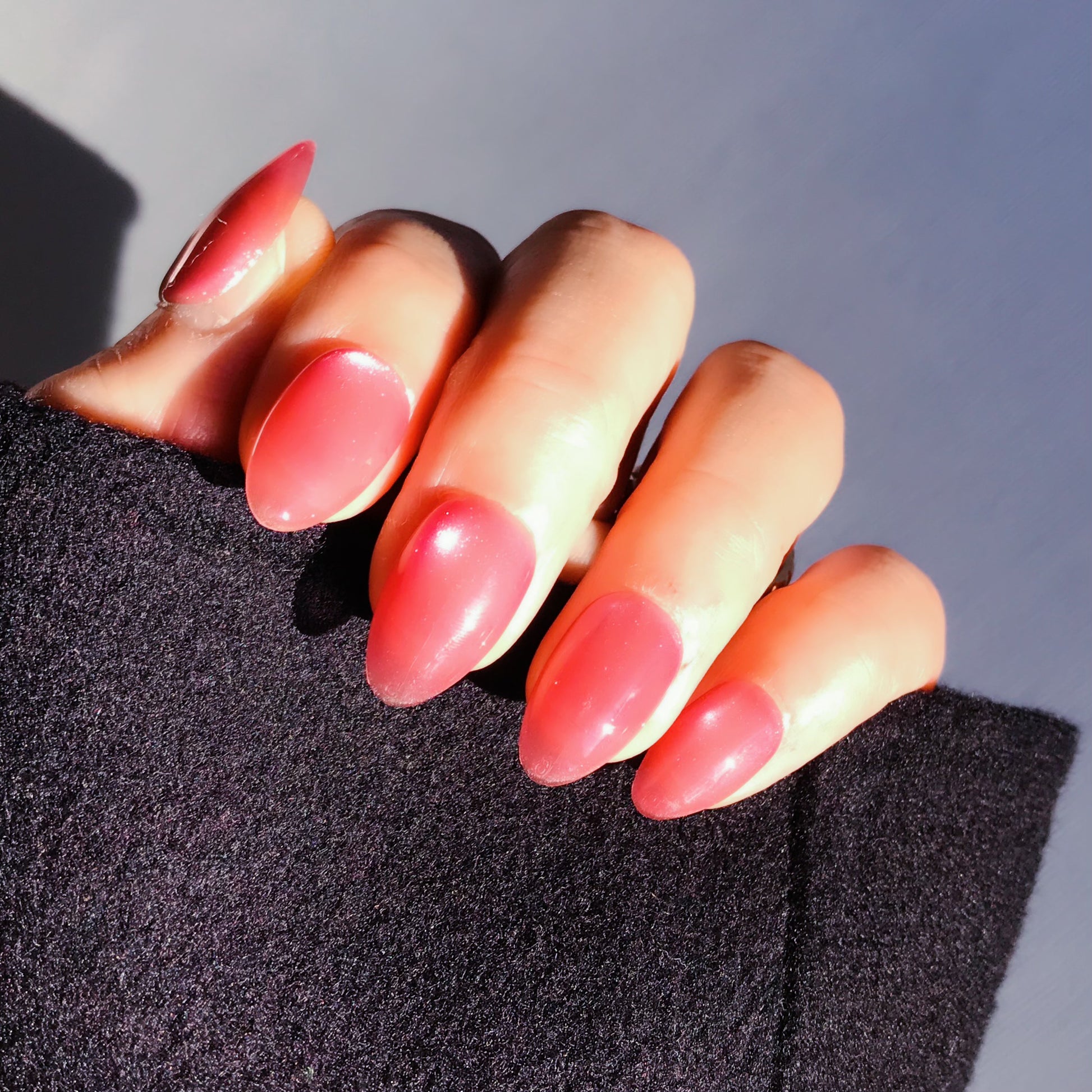 Close-up of a hand with pink press-on nails in almond shape.  