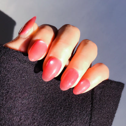 Close-up of a hand with pink press-on nails in almond shape.  