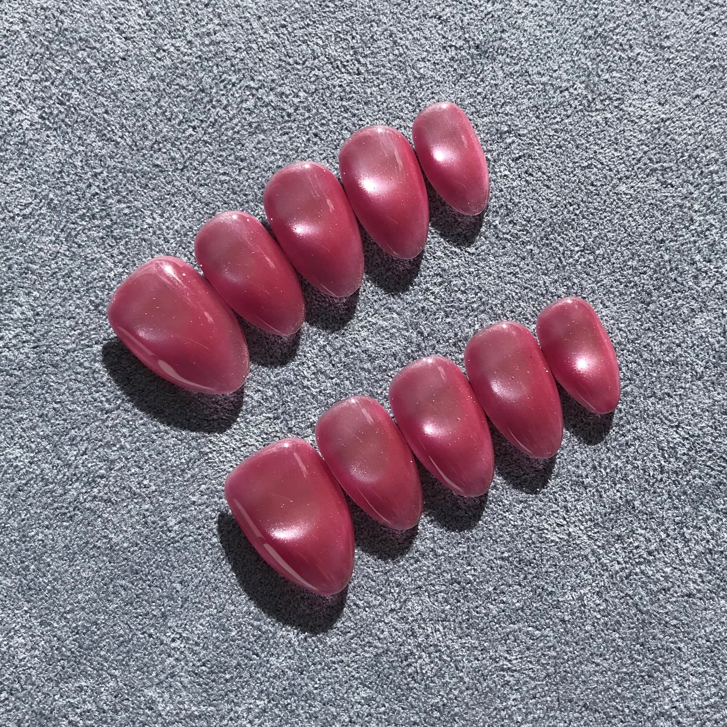 Premium handmade pink press-on nails in medium almond shape  with glittering cat eye design. 