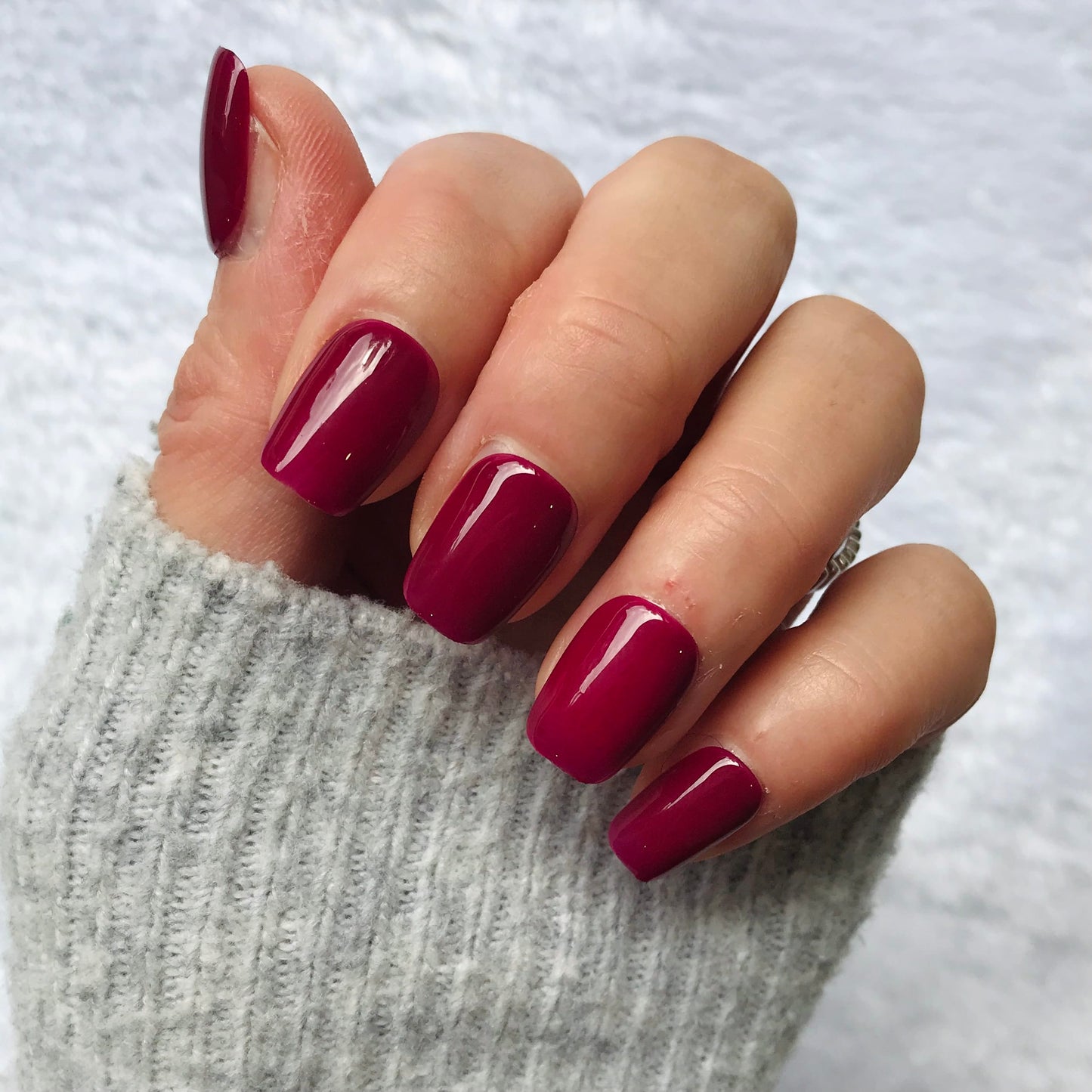 Hand with handmade glossy magenta press-on nails.
