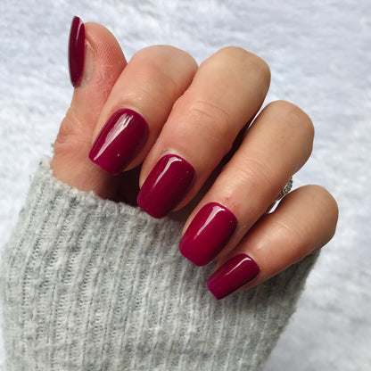 Hand with handmade glossy magenta press-on nails.