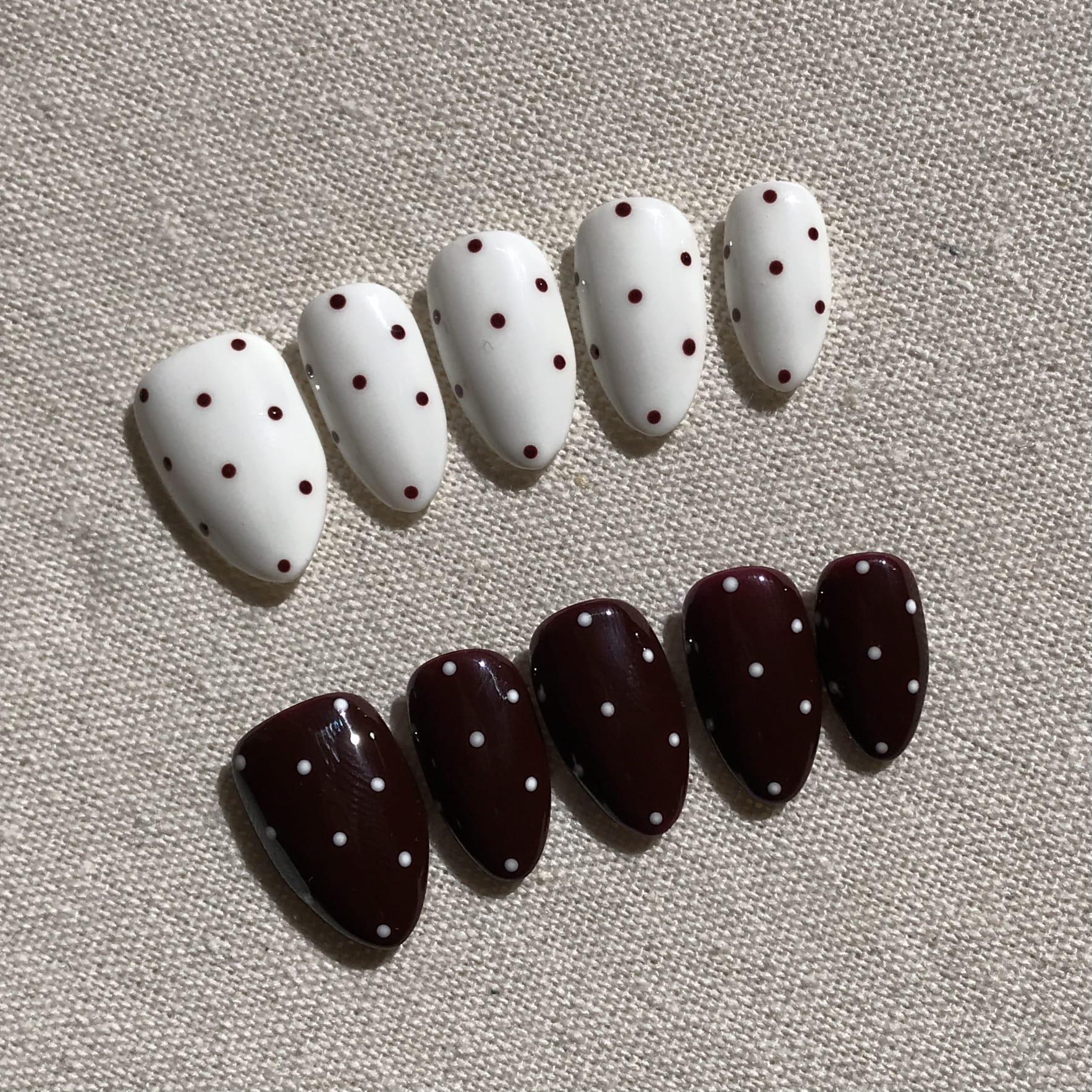 Calm Storm premium press-on nails in white and brown with polka dot patterns .