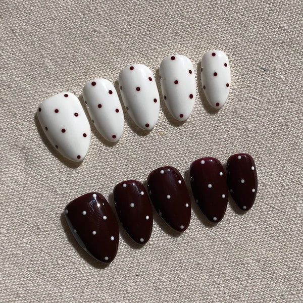 Calm Storm premium press-on nails in white and brown with polka dot patterns .
