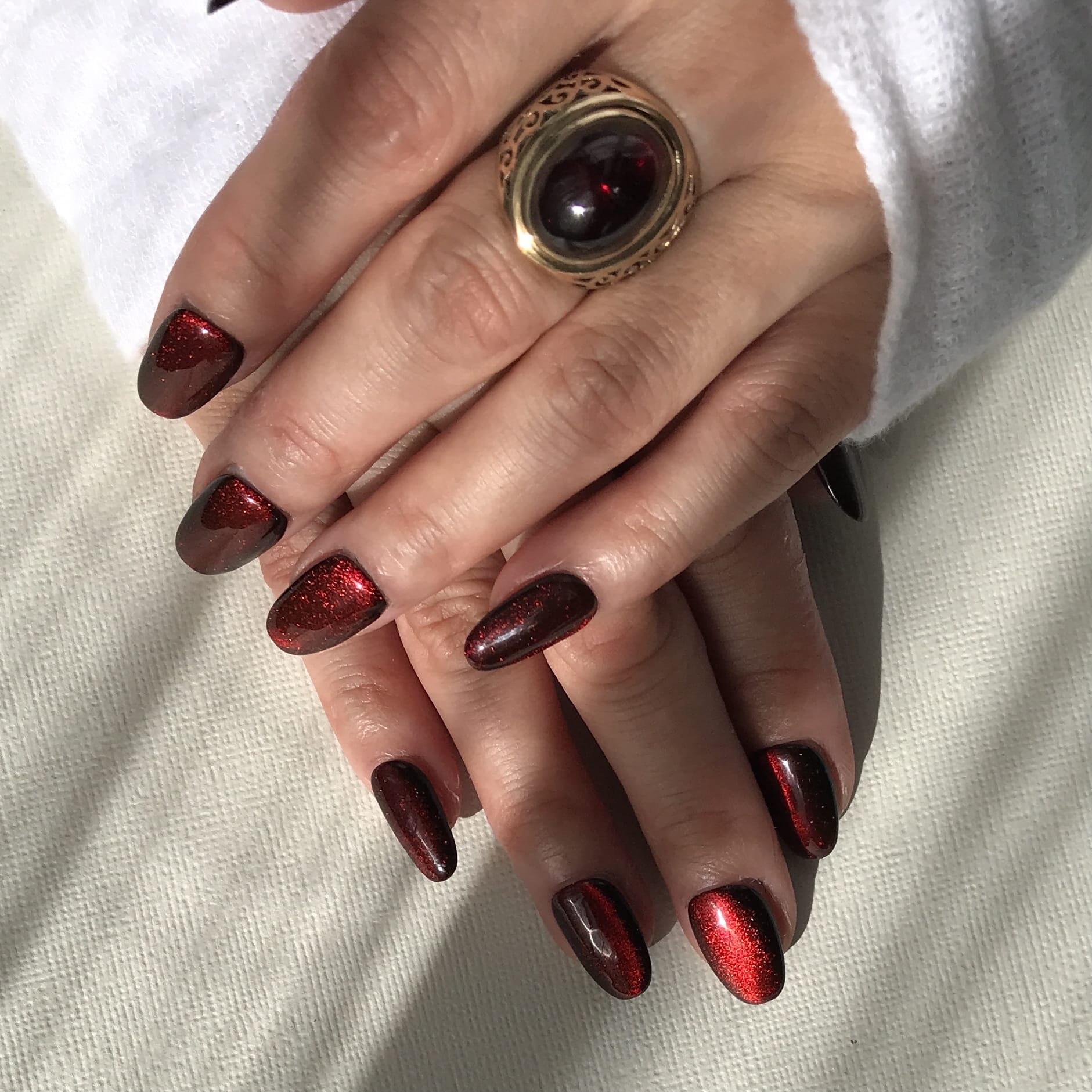 Hand model of dark red cat eye press-on nails in medium oval. 