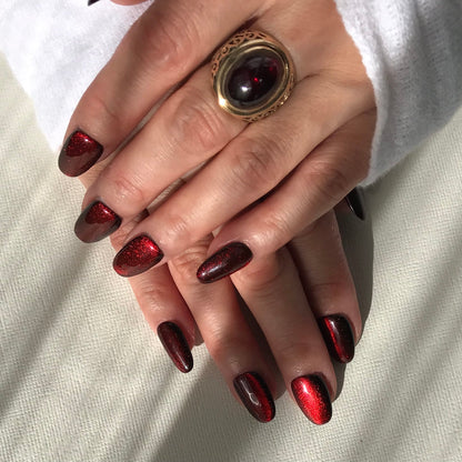 Hand model of dark red cat eye press-on nails in medium oval. 