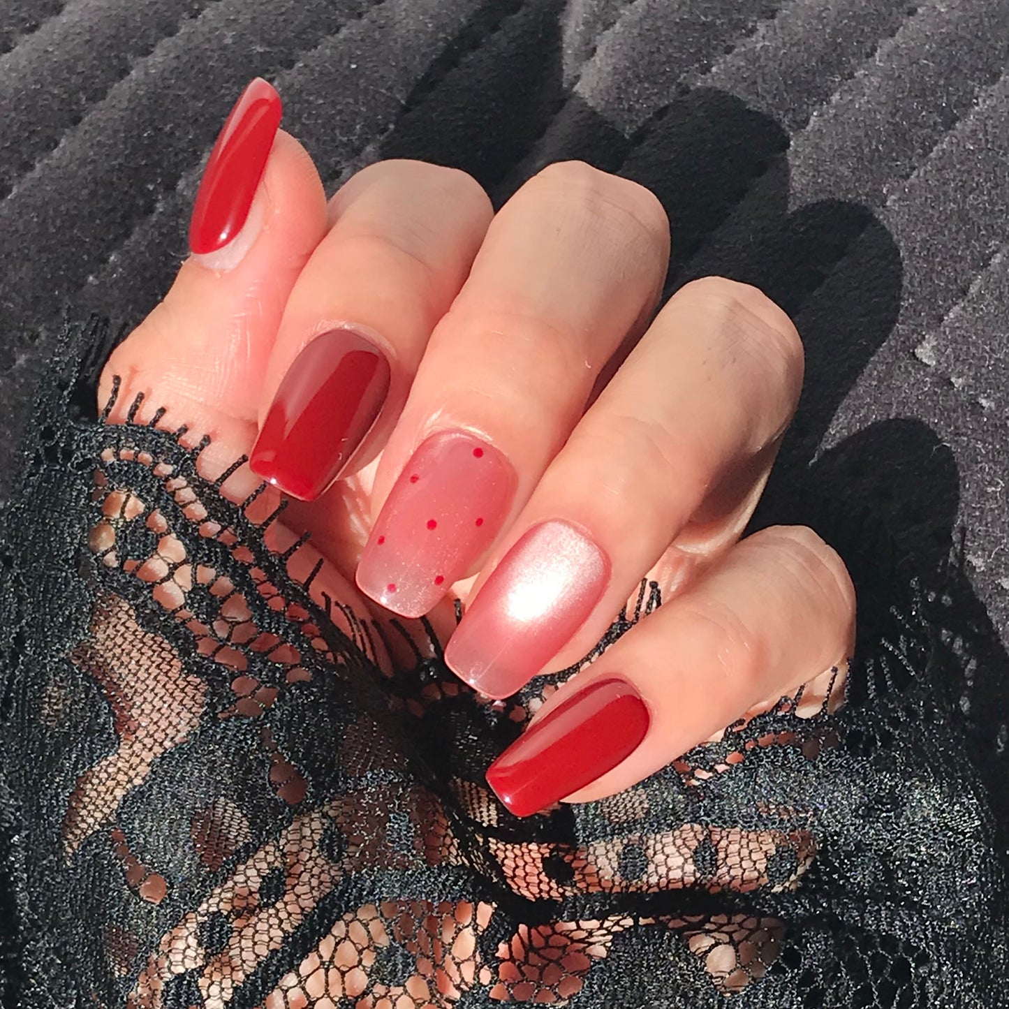 Close-up of a hand with handmade red and pink gradient press-on nails 
