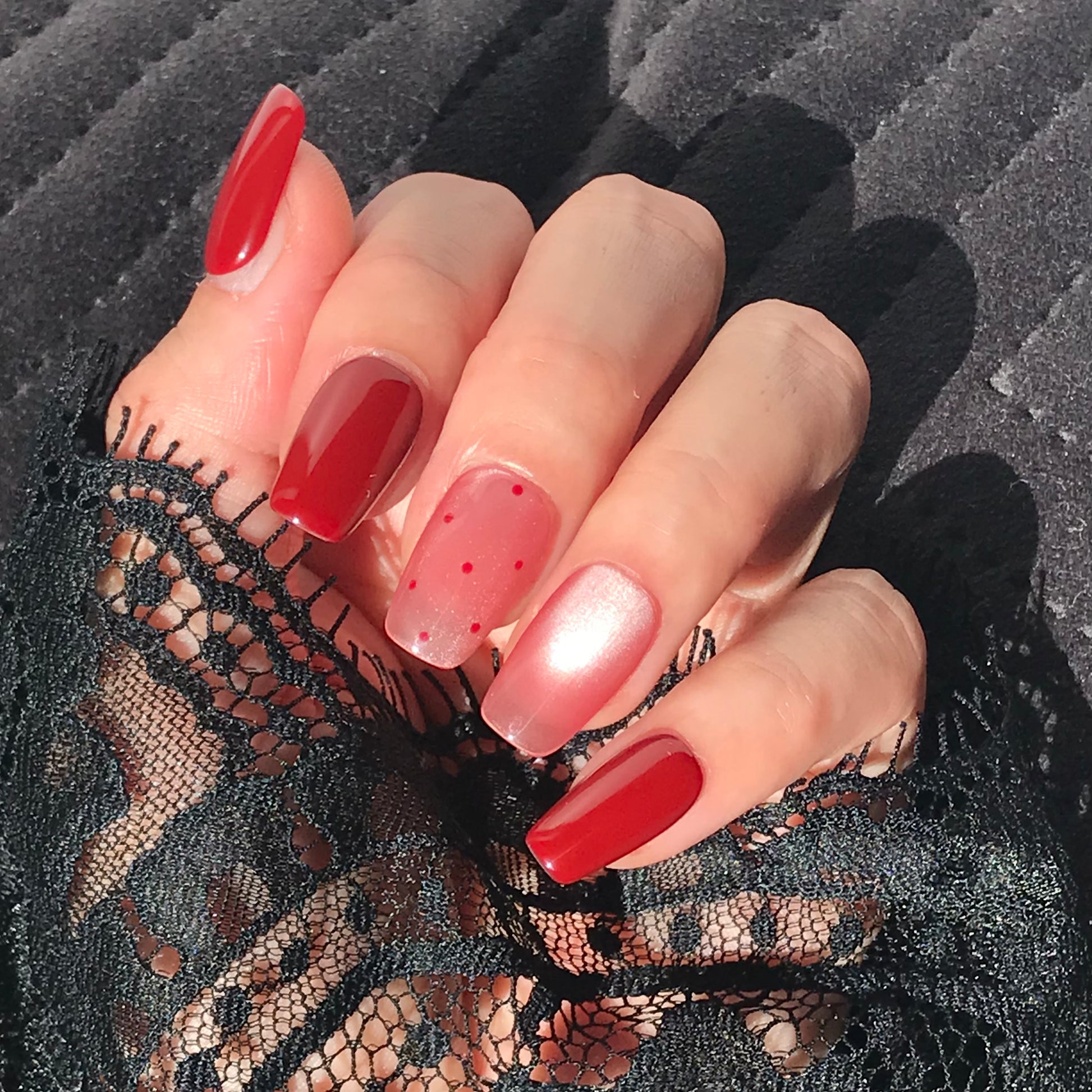 Close-up of a hand with handmade red and pink gradient press-on nails 