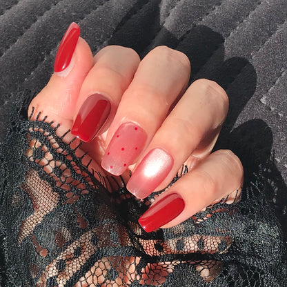 Close-up of a hand with handmade red and pink gradient press-on nails 