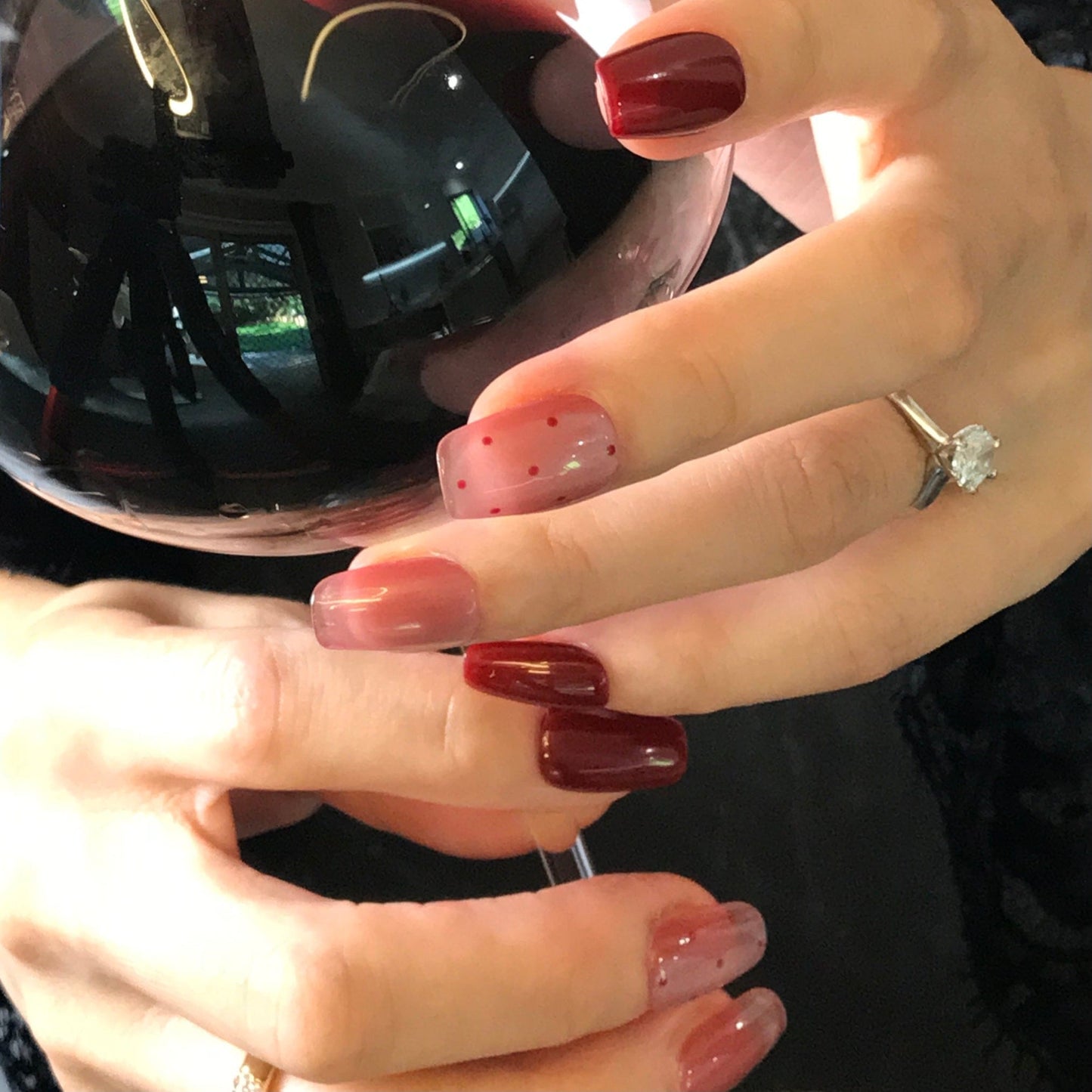 Hands modelling salon quality red press-on nails with pink cat eye design.