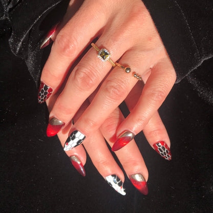 Close up of luxury press-on nails with nail art featuring snakeskin, ruby red, gold, black and white. 